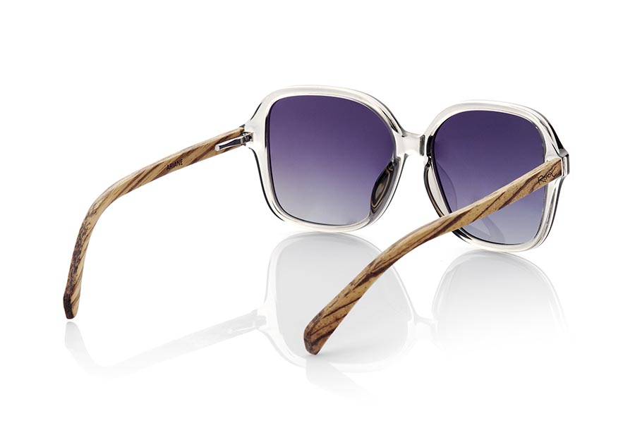 Wood eyewear of Zebrano MANARA. MANARA glasses have an avant-garde and sophisticated design that will not go unnoticed. Its slightly oversized square front in glossy transparent smoke gray, together with the temples anchored in the center of the frame, give it a touch of modernity. These glasses are specially designed for women looking for an innovative and elegant look. The temples are made of Zebrano wood with dark and elegant veins that contrast with the color of the frame, and they are mounted on gradient gray lenses that provide complete protection against UV rays. If you want to be fashionable with a touch of originality, ARIANE glasses are the perfect choice. Front measurement approx: 144x56mm for Wholesale & Retail | Root Sunglasses® 